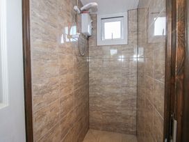 A shower area with tiled walls and a window at Sharon's Shepherd Hut in Oswestry