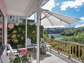 A deck with chairs and a table overlooking a river at Mayhurst in Looe