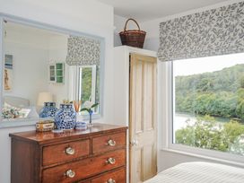 A bedroom with a dresser and window at Mayhurst in Looe