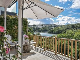 An outdoor space with a table and chairs overlooking a river at Mayhurst in Looe