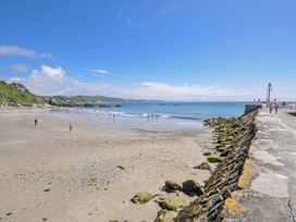 A beach with people swimming and a pier at Mayhurst in Looe