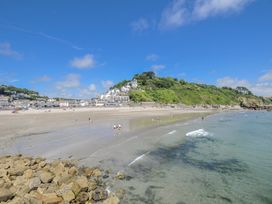 A beach with people and houses at Mayhurst in Looe