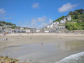 A beach with people walking at Mayhurst in Looe
