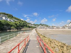 A pier leading to a beach with houses in the background at Mayhurst in Looe