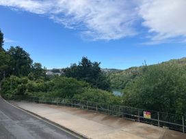 A view from a road with trees and a body of water at Mayhurst, Looe
