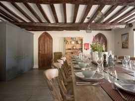 A dining room with a long table set for meals at Holwell Farmhouse in Bampton
