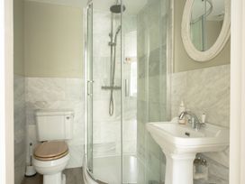 A bathroom with a sink, toilet, shower, and mirror at Holwell Farmhouse in Bampton
