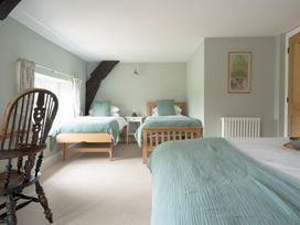 A bedroom with two beds and a chair at Holwell Farmhouse in Bampton