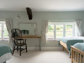 A bedroom with beds, a chair, a table, and a mirror at Holwell Farmhouse in Bampton