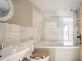 A bathroom with a sink, toilet, bathtub and shower at Holwell Farmhouse in Bampton