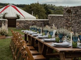 An outdoor dining area with a long table set up at Holwell Farmhouse in Bampton