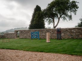 A garden with a stone wall and games at Holwell Farmhouse in Bampton