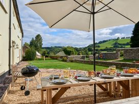A dining table with food and drinks under an umbrella at Holwell Farmhouse in Bampton