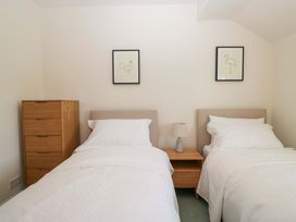 A bedroom with two beds, a nightstand, and a dresser at 11 Tram Lane in Kirkby Lonsdale