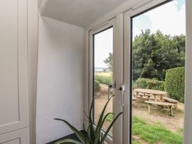 A window with a plant overlooking a garden with seating at Garreg Fawr 