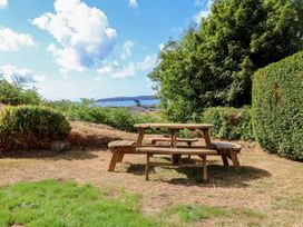 A garden with a wooden table and benches overlooking the sea at Garreg Fawr