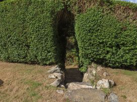 A stone pathway through a hedge in a garden at Garreg Fawr 