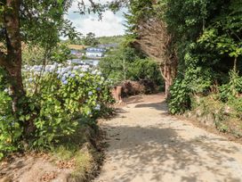 A pathway with flowers and trees leading to houses at Garreg Fawr in 