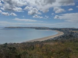 A beach with a town in the background at Garreg Fawr Llanbedrog