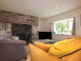 A living room with a fireplace and a television at Rosewin Farmhouse near St Minver