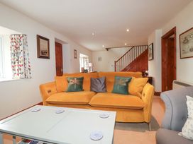 A living room with a yellow sofa and coffee table at Rosewin Farmhouse near St Minver