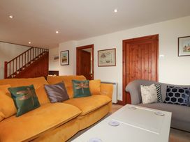 A living room with a yellow sofa and gray chair at Rosewin Farmhouse near St Minver