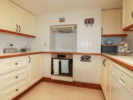A kitchen with cabinets, stove, sink, and dishwasher at Rosewin Farmhouse near St Minver