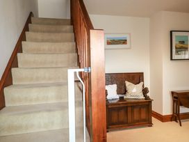 A hallway with stairs and a bench at Rosewin Farmhouse near St Minver