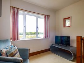 A sitting room with a window and television at Rosewin Farmhouse near St Minver