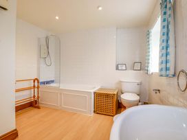 A bathroom with a bathtub, toilet, and shower at Rosewin Farmhouse near St Minver