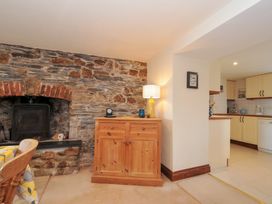 A living room with a fireplace and cabinet at Rosewin Farmhouse near St Minver