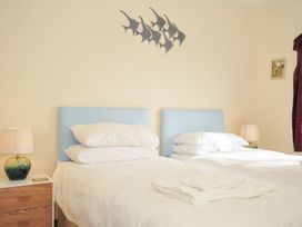 A bedroom with two beds and a bedside lamp at Rosewin Farmhouse near St Minver