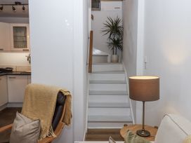 A living room with a staircase and kitchen cabinetry at The Workshop in Mary Tavy