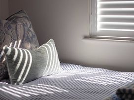 A bed with striped bedding and pillows at Wood Cottage 