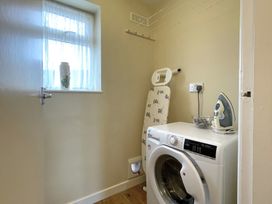A laundry room with a washing machine and ironing equipment at Roseberry in Whitby