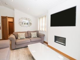 A living room with a sofa and television at Easedale Lodge, Waterside Wood 2, White Cross Bay near Windermere