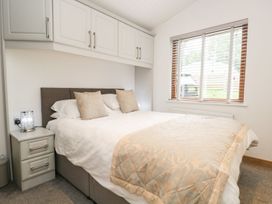 A bedroom with a bed and bedside table at Easedale Lodge near Waterside Wood 2, White Cross Bay near Windermere