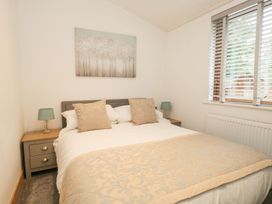 A bedroom with a bed and bedside table at Easedale Lodge, Waterside Wood 2, White Cross Bay near Windermere