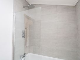 A shower area with glass panel and bathtub at Easedale Lodge, Waterside Wood 2, White Cross Bay near Windermere