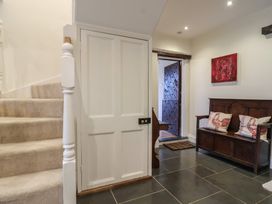 A hallway with a bench and staircase at The Old Manor House in Lifton