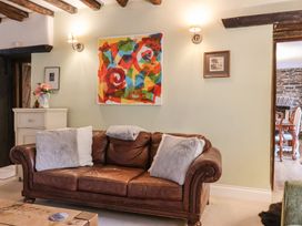 A living room with a leather sofa and artwork at The Old Manor House in Lifton