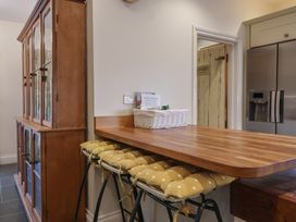 A kitchen with a wooden island and bar stools at The Old Manor House in Lifton