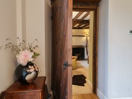A hallway with a large wooden door and vase on a table at The Old Manor House in Lifton