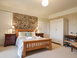 A bedroom with a bed, nightstands, a wardrobe, and a chair at The Old Manor House in Lifton