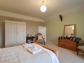 A bedroom with a bed, wardrobe, and chair at The Old Manor House in Lifton