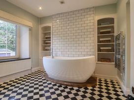A bathroom with a bathtub and shelves at The Old Manor House in Lifton