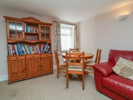 A dining room with a table, chairs, and a bookshelf at Honey Cottage Ilfracombe