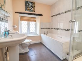 A bathroom with a sink, toilet, bathtub, and shower enclosure at Honey Cottage in Ilfracombe
