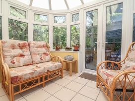 A conservatory with seating and plants at Honey Cottage in Ilfracombe