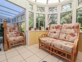 A conservatory with rattan chair and sofa at Honey Cottage in Ilfracombe